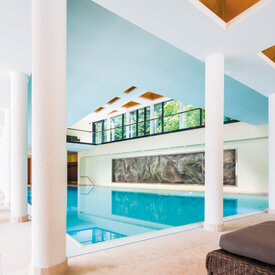 Das Schwimmbad im Wellnesshotel im Harz ist lichtdurchflutet und farbenfroh und mit Liegen bestückt.