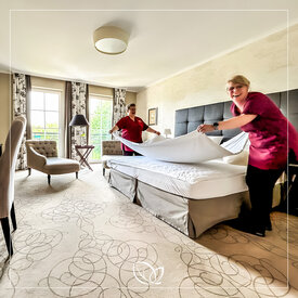Housekeeping mit Spaßfaktor Zwei Mitarbeiterinnen beziehen ein Bett im Gästezimmer neu und haben dabei viel Spaß.